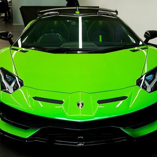 Sleek luminous green Lamborghini showcased in an elegant indoor showroom, epitomizing luxury and speed.